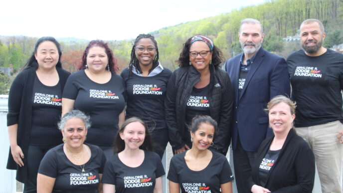 A group of colleagues poses together on an outdoor rooftop garden.